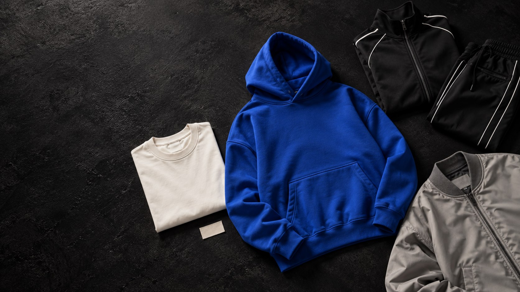 Concept apparel collection with a blue hoodie, ivory shirt, tracksuit and stone jacket